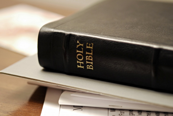 A Bible lying on a table on top of paper.