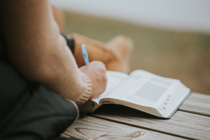 A person writing notes in a Bible.