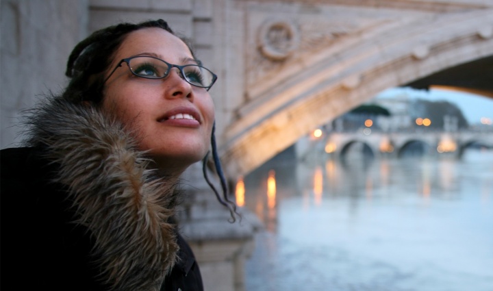 A woman standing beside an old bridge.