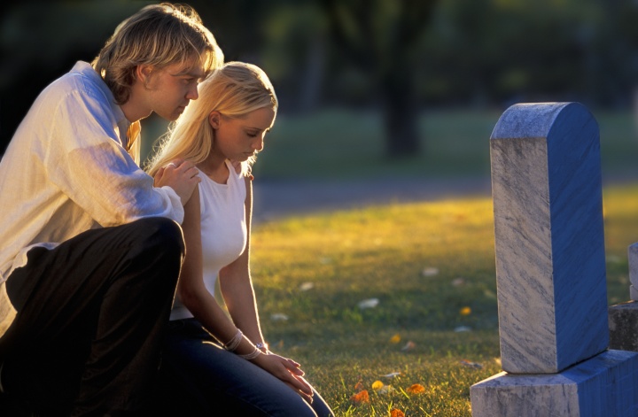 A young couple by a grave stone.