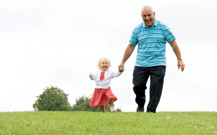 A grandfather holding his little grandaughter's hands.