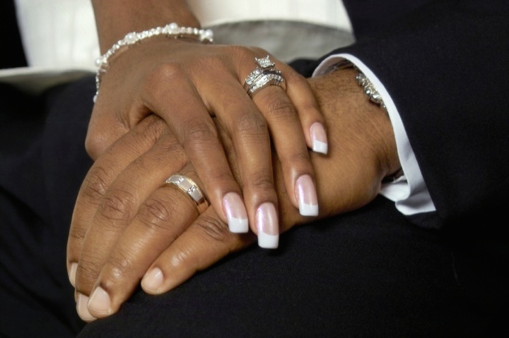 A couple holding hands showing their wedding rings.