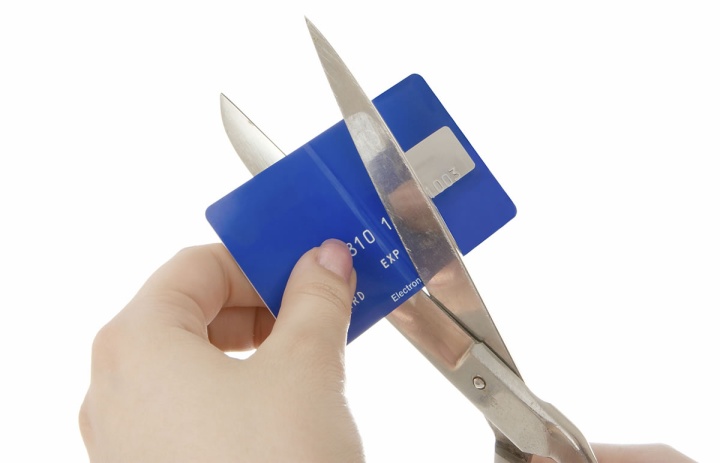 A person cutting a credit card with a pair of scissors.