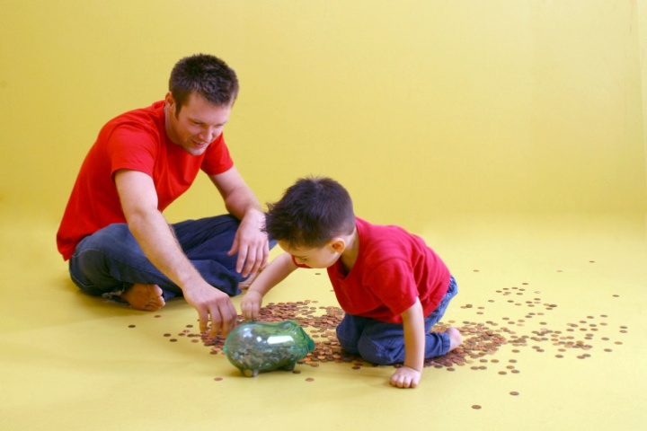 A father and son counting pennies from a glass jar.