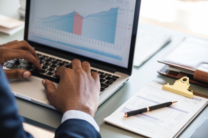 A person working on a laptop with financial charts.