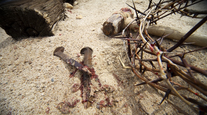 Photo illustration of a crown of thorns, old nails, hammer and wood beam.