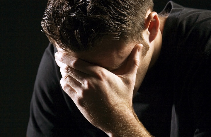 A young man holding his head with hands as in sorrow or remorse.