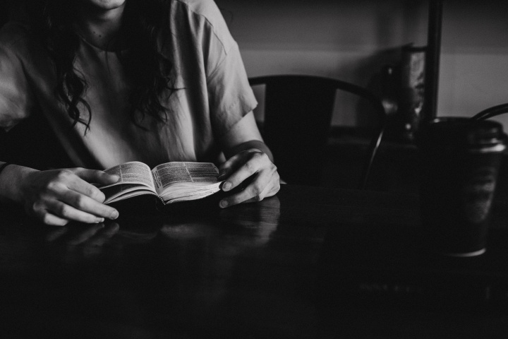 A woman reading a Bible in a coffee shop.