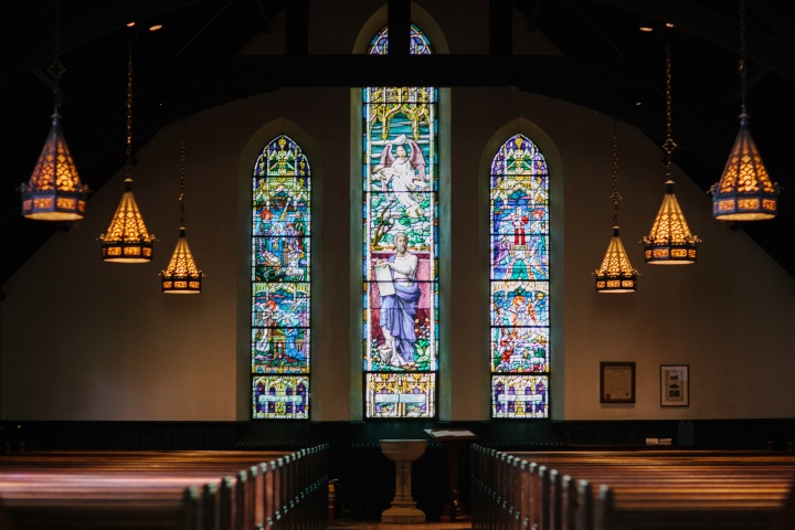 Inside a large church with stain glass windows.