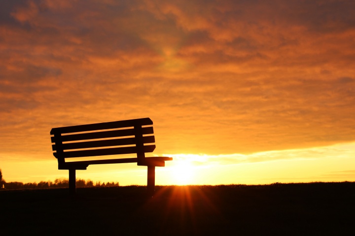 A empty bench with the sun setting.