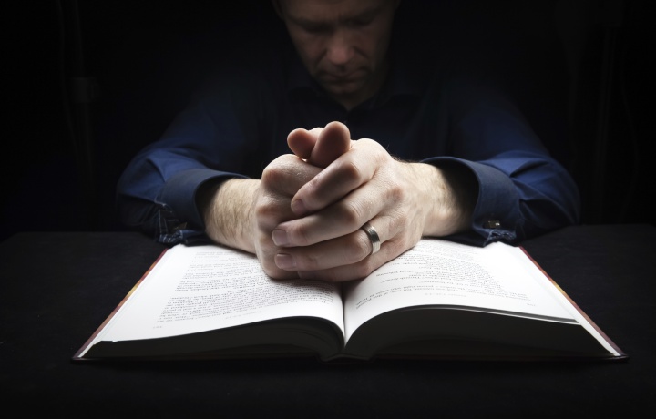 A person praying with a Bible.