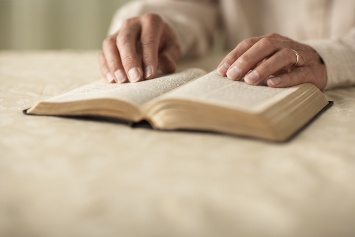 A person's hands on top of a Bible.