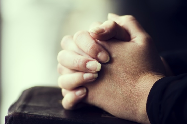 Womans hands on top of a Bible.