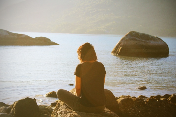 A woman sitting by a body of water.