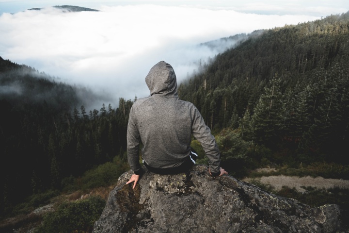 A person sitting on a rock looking over a valley.