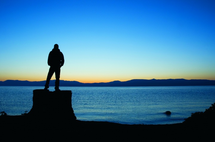 Silhouette of a man looking out over a body of water.