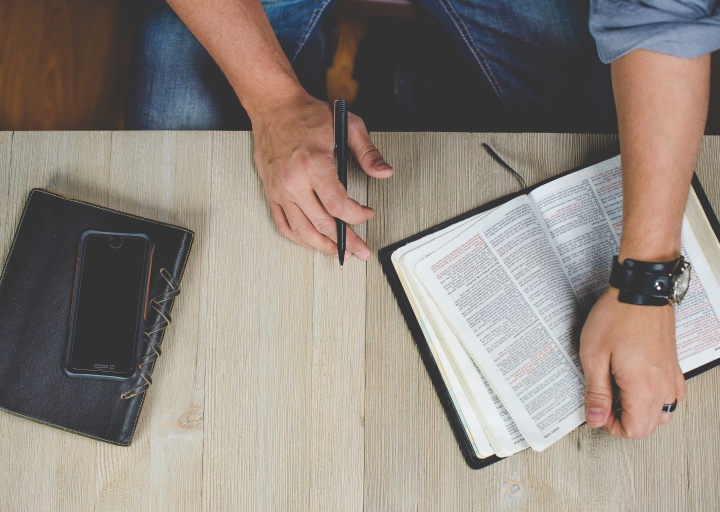 A man studying a Bible on a table.