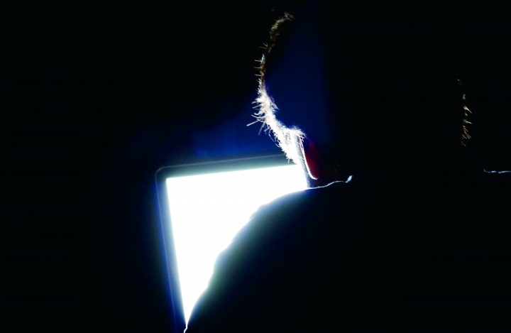A man looking at a computer screen in a dark room.