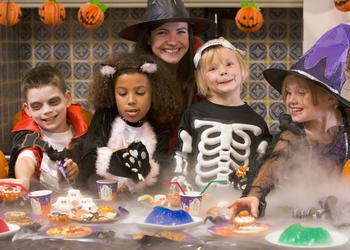 A mom and four kids eating Halloween treats.