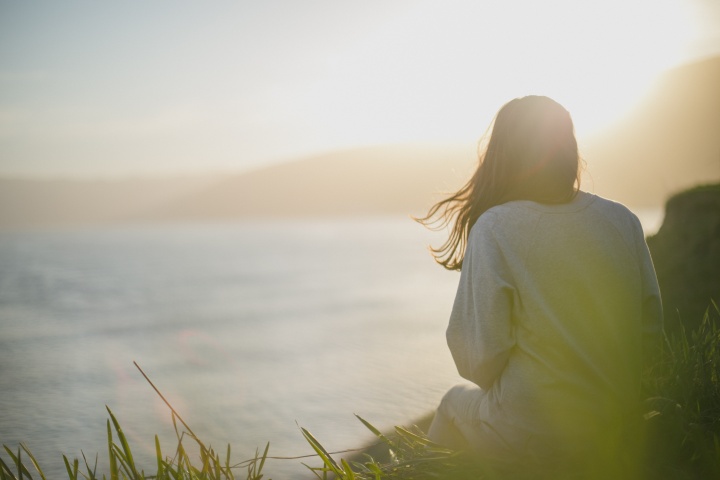 A woman looking at sunset over a body of water.