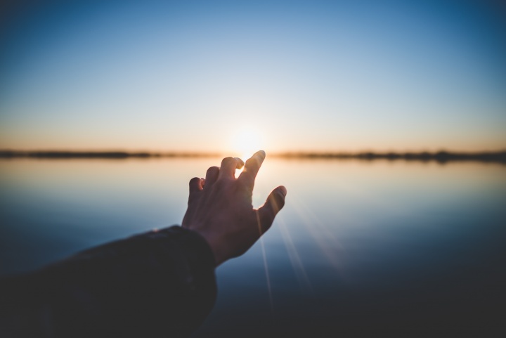 A hand reaching out over water.