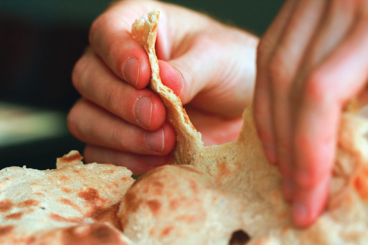 A person tearing unleavened bread.