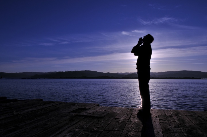 A person looking up to the sky and praying.