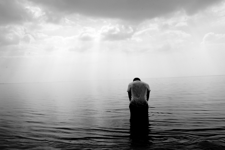 A man standing waist deep in a lake.