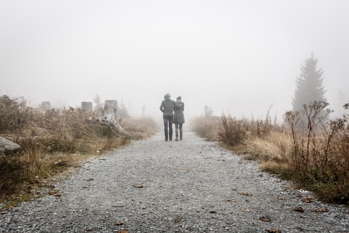 Two people walking together on a gravel path.