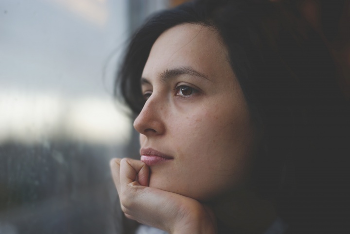 An upclose photo of woman's face looking out a window.