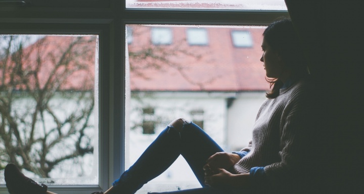 A young woman sitting by a window.