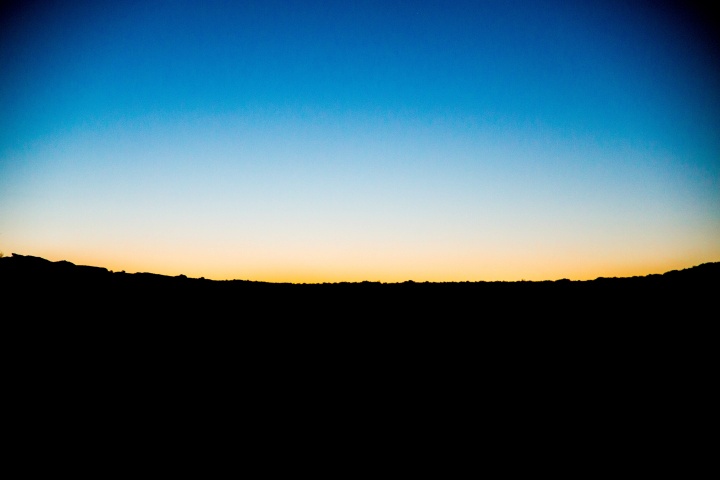 A sunset over a dark hill.