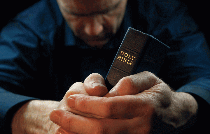 A man praying over his Bible