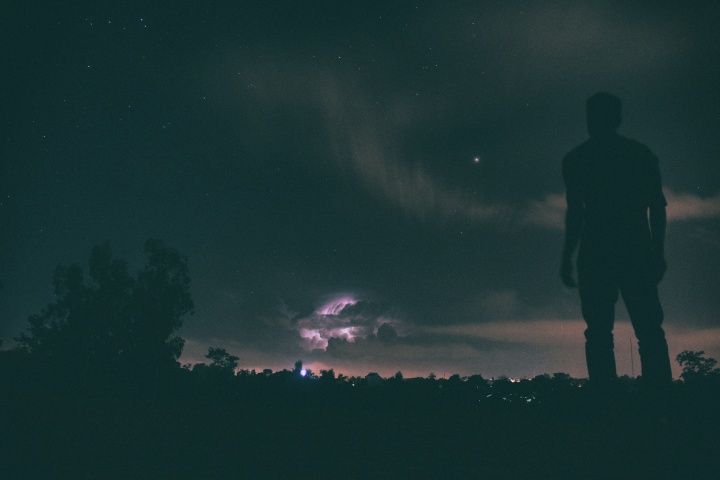 A person standing outside looking up at stars in the sky.