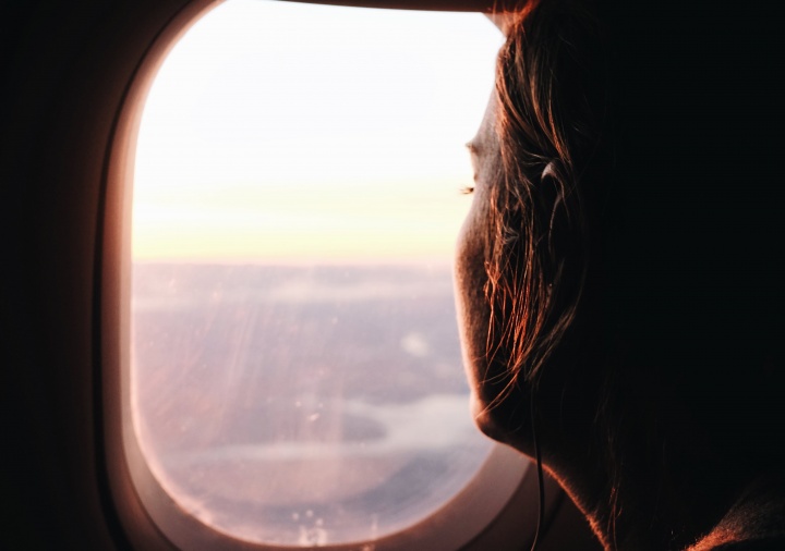 A young women looking out the window of an airplane. 