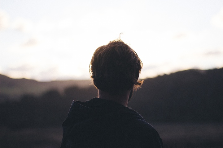 A young man looking at a sunset.