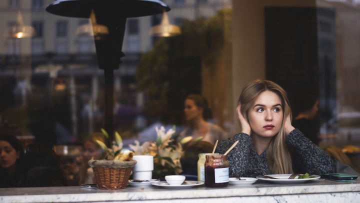 A young woman sitting at restaurant counter looking out the front window.