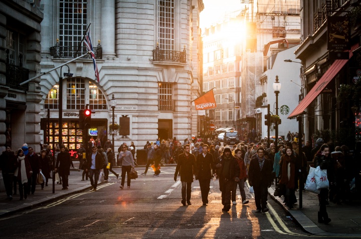 People walking a crowded city street and sidewalk.