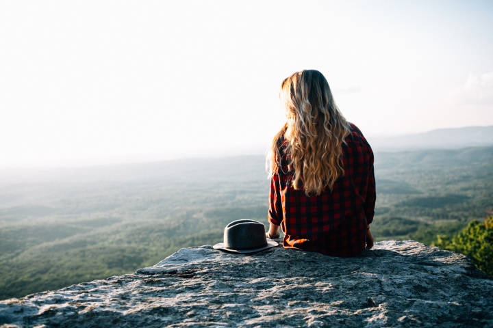 A young woman sitting on the edge of a rock.