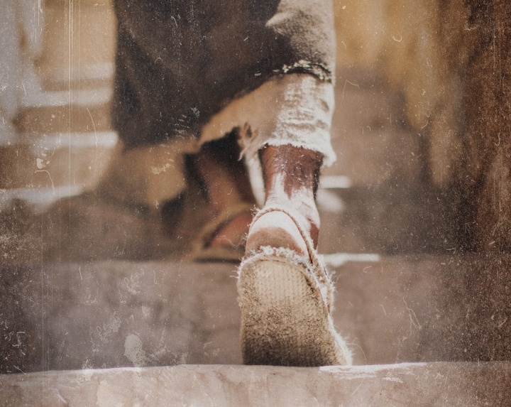 A person wearing sandals walking about dusty steps.