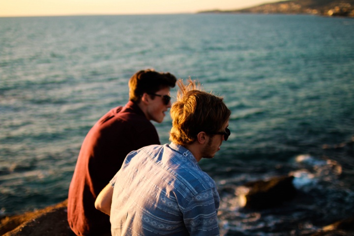 Two young men talking to each other by the ocean.