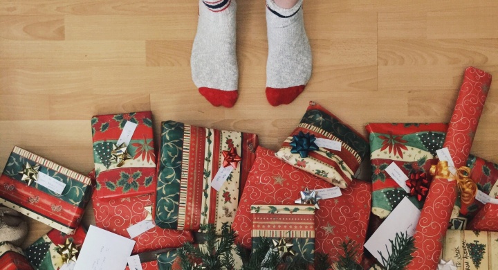A person with socks standing right beside Christmas gifts. 