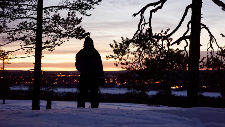 A person standing in the snow looking out over a town.