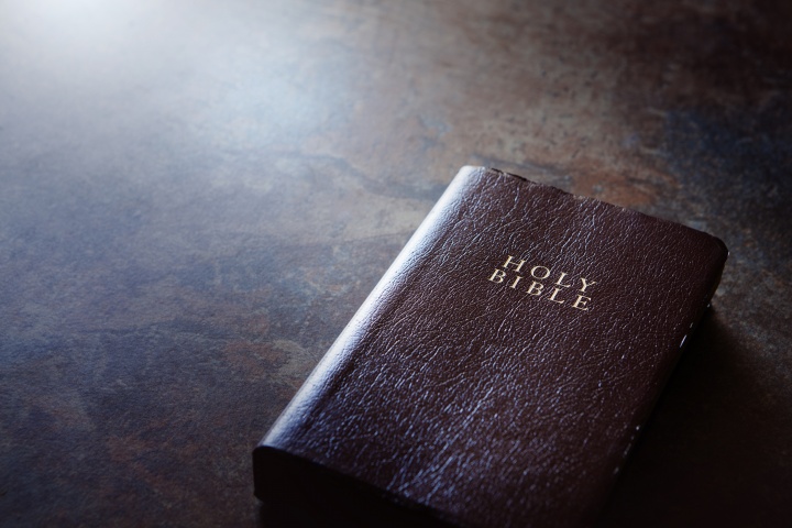 A Bible laying on a brown table.