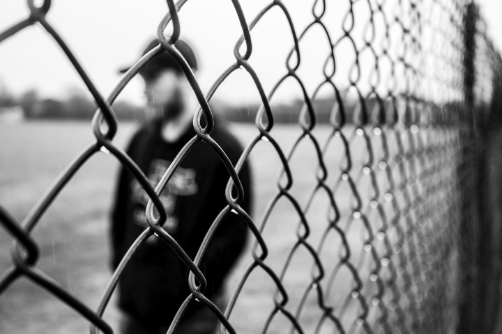 A man standing behind a fence.