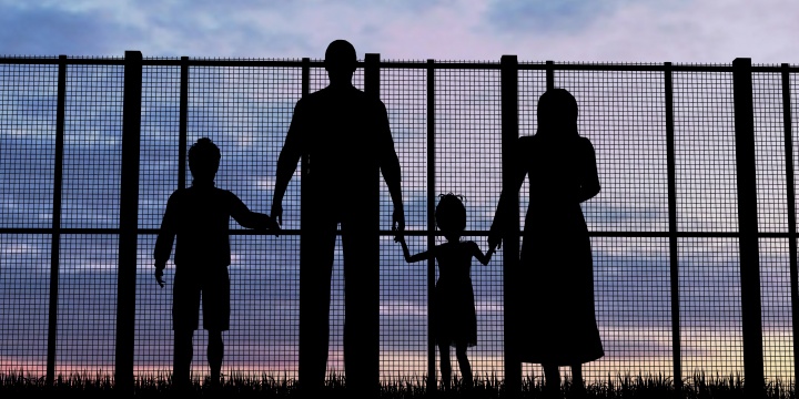 A family of four looking through a tall fence.