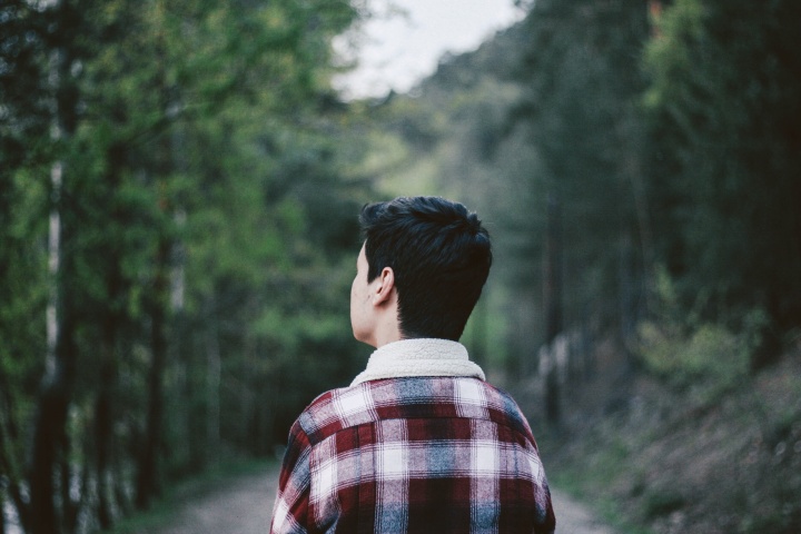 A young man walking looking down a path.