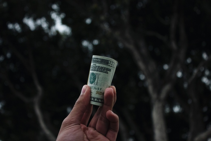 A man holding a folded $20 bill. 