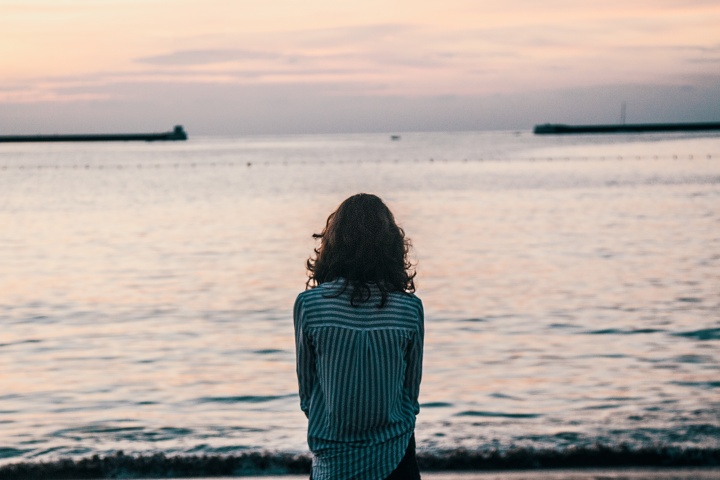 A woman sitting by a large body of water.