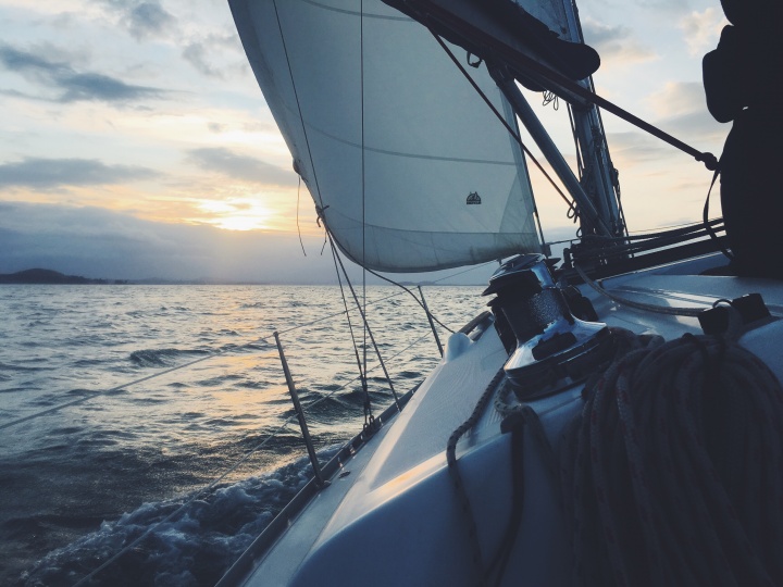 A sailboat gliding across the sea early in the morning.